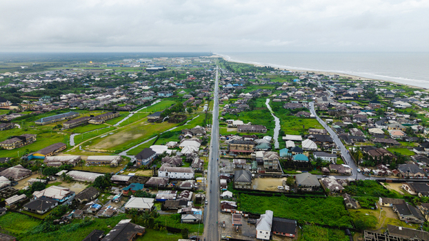 Aerial view of the coastal town of Kwa Ibo featuring a long straight road cutting through residential areas lush green vegetation and the coastline of Ibeno Beach Kwa Ibo Akwa Ibom Nigeria.