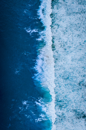 Aerial view of powerful ocean waves crashing against the coastline at Sandpatch with deep blue water and white sea foam patterns in Albany Western Australia Australia. Aerial view of powerful ocean waves crashing against the coastline at Sandpatch with deep blue water and white sea foam patterns in Albany Western Australia Australia.