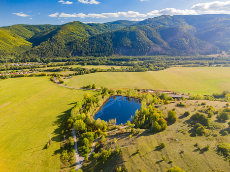 Aerial view of the Gudronove jamy acid tar lagoons surrounded by trees and green fields with the Low Tatras mountains in the background in Predajna Banskobystricky kraj Slovakia. Aerial view of the Gudronove jamy acid tar lagoons surrounded by trees and green fields with the Low Tatras mountains in the background in Predajna Banskobystricky kraj Slovakia.