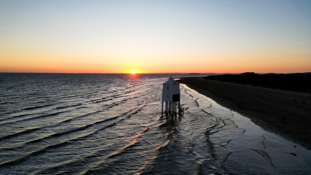Aerial view of the Burnham on Sea Low Lighthouse standing on wooden stilts on the sandy beach at sunset with gentle waves washing the shore in Burnham on Sea England United Kingdom. Aerial view of the Burnham on Sea Low Lighthouse standing on wooden stilts on the sandy beach at sunset with gentle waves washing the shore in Burnham on Sea England United Kingdom.