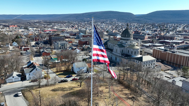 Aerial view of the Cathedral of the Blessed Sacrament with a large American flag flying in the foreground overlooking the city of Altoona Pennsylvania United States.