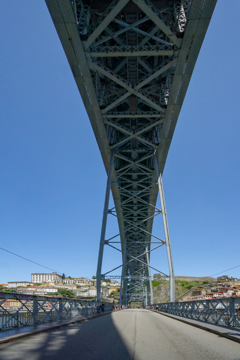 View of the Dom Luís I Bridge s steel framework against a clear blue sky casting shadows on the road in Porto Porto Portugal. View of the Dom Luís I Bridge s steel framework against a clear blue sky casting shadows on the road in Porto Porto Portugal.