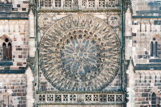 Aerial view of the intricate Gothic rose window and detailed stone carvings on the facade of St. Lorenz church Nurnberg Bayern Germany.