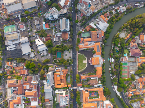 Aerial view of the urban landscape in Surabaya featuring dense buildings with orange rooftops a winding river lush green trees and busy roads in Surabaya East Java Indonesia. Aerial view of the urban landscape in Surabaya featuring dense buildings with orange rooftops a winding river lush green trees and busy roads in Surabaya East Java Indonesia.