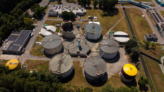 Aerial view of a wastewater treatment plant featuring large circular sedimentation tanks and industrial infrastructure surrounded by greenery in Milan Lombardy Italy. Aerial view of a wastewater treatment plant featuring large circular sedimentation tanks and industrial infrastructure surrounded by greenery in Milan Lombardy Italy.