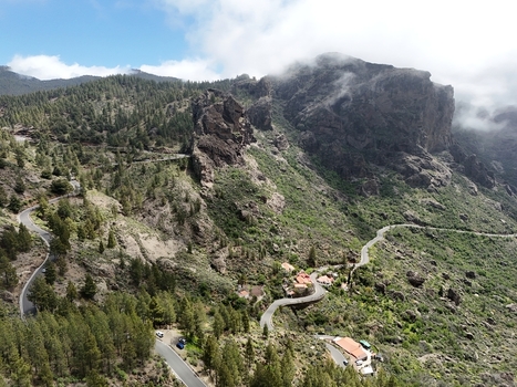 Aerial view of winding roads carve through the lush green landscape leading to the Roque Nublo peak shrouded in mist La Culata Canarias Spain. Aerial view of winding roads carve through the lush green landscape leading to the Roque Nublo peak shrouded in mist La Culata Canarias Spain.