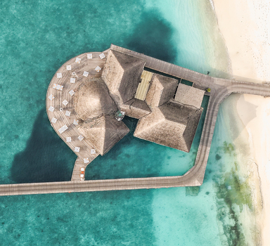 Aerial view of a luxury overwater resort building with thatch roofs and a circular wooden deck over turquoise ocean water at Hoarafushi Haa Alif Atoll Maldives. Aerial view of a luxury overwater resort building with thatch roofs and a circular wooden deck over turquoise ocean water at Hoarafushi Haa Alif Atoll Maldives.