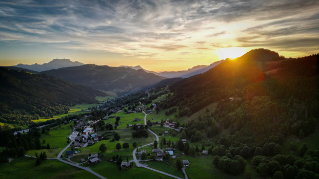 Aerial view of sunbeams dance across the verdant valley illuminating the quaint village nestled amongst rolling hills La Clusaz Auvergne Rhône Alpes France. Aerial view of sunbeams dance across the verdant valley illuminating the quaint village nestled amongst rolling hills La Clusaz Auvergne Rhône Alpes France.