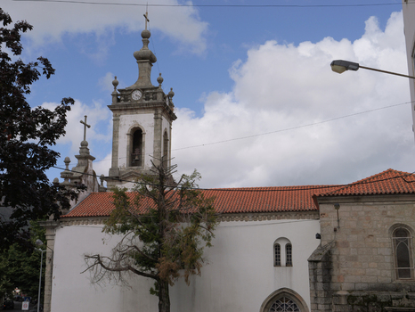 View of Igreja de Nossa Senhora da Conceicao da Covilha with its bell tower stone walls and tiled roof under a blue sky in Covilha Castelo Branco Portugal.