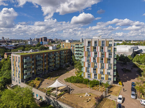 Aerial view of modern apartment buildings with colorful facades and green roofs surrounding a courtyard with a white canopy in London England United Kingdom. Aerial view of modern apartment buildings with colorful facades and green roofs surrounding a courtyard with a white canopy in London England United Kingdom.