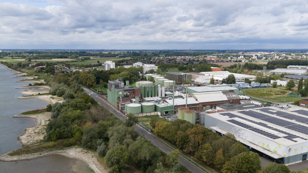 Monheim am Rhein Germany 04 September 2026 Aerial view of UNIFERM GmbH Co. KG industrial facility by the Rhine river featuring storage tanks factory buildings with solar panels and greenery.