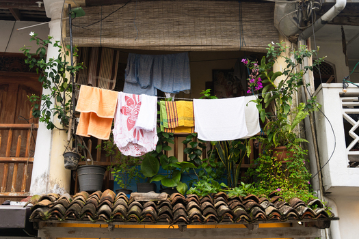 View of colorful laundry hanging on a balcony line surrounded by lush potted plants and traditional terracotta roof tiles Galle Southern Province Sri Lanka.