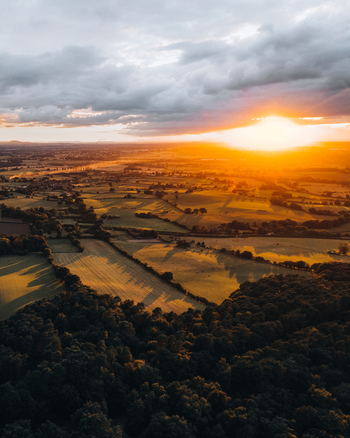Aerial view of Cannock Chase Forest at sunset featuring rolling green fields dense woodland and golden light across the landscape in Staffordshire England United Kingdom. Aerial view of Cannock Chase Forest at sunset featuring rolling green fields dense woodland and golden light across the landscape in Staffordshire England United Kingdom.