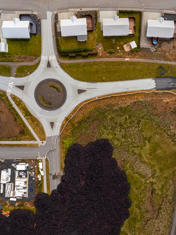 Aerial view of a modern roundabout and residential houses situated next to a dark solidified volcanic lava flow in Iceland. Aerial view of a modern roundabout and residential houses situated next to a dark solidified volcanic lava flow in Iceland.
