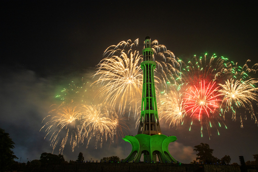 View of the illuminated Minar e Pakistan monument surrounded by vibrant fireworks in the night sky in Lahore Punjab Pakistan.