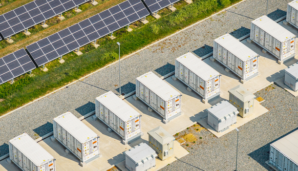 Aerial view of modular battery storage units operating beside photovoltaic solar panels at a modern renewable energy facility in Italy. Aerial view of modular battery storage units operating beside photovoltaic solar panels at a modern renewable energy facility in Italy.