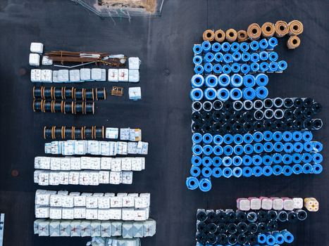 Aerial view of industrial storage yard featuring rows of blue black and white construction material coils and pipes arranged on asphalt in Jelgava Latvia. Aerial view of industrial storage yard featuring rows of blue black and white construction material coils and pipes arranged on asphalt in Jelgava Latvia.