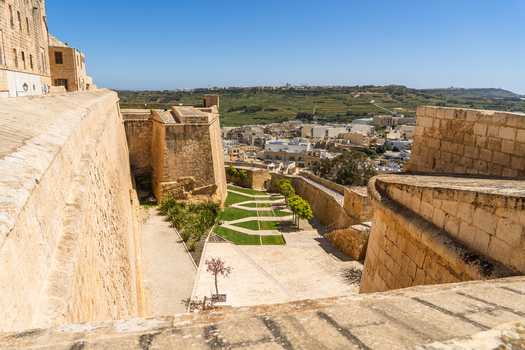 View of the historic stone fortifications with green gardens and a panoramic view of the surrounding landscape and town in Zebbug Gozo Region Malta. View of the historic stone fortifications with green gardens and a panoramic view of the surrounding landscape and town in Zebbug Gozo Region Malta.