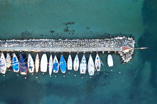 Aerial view of sailboats moored at a stone pier in the turquoise waters of Lake Geneva in Morges Vaud Switzerland. Aerial view of sailboats moored at a stone pier in the turquoise waters of Lake Geneva in Morges Vaud Switzerland.