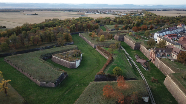 Aerial view of the Vauban walled city of Neuf Brisach featuring iconic star shaped fortifications lush grass autumn trees and historic stone walls in Neuf Brisach Grand Est France. Aerial view of the Vauban walled city of Neuf Brisach featuring iconic star shaped fortifications lush grass autumn trees and historic stone walls in Neuf Brisach Grand Est France.