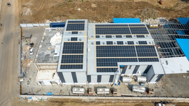 Aerial view of a modern warehouse facility featuring extensive solar panel installations on the roof located in an industrial area in Bhiwandi Maharashtra India. Aerial view of a modern warehouse facility featuring extensive solar panel installations on the roof located in an industrial area in Bhiwandi Maharashtra India.