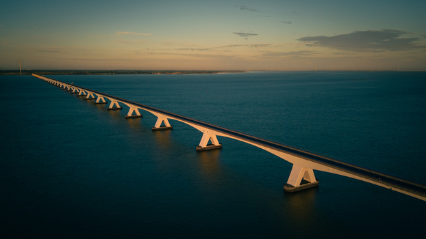 Aerial view of the Zeeland Bridge spanning the calm waters of the Oosterschelde estuary during the golden hour in Zierikzee Zeeland Netherlands. Aerial view of the Zeeland Bridge spanning the calm waters of the Oosterschelde estuary during the golden hour in Zierikzee Zeeland Netherlands.