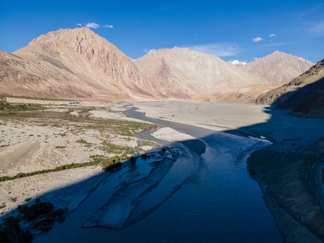 Aerial view of the Shyok River winding through the arid mountainous landscape of the Himalayas with rocky riverbanks and clear blue sky in Ladakh Division Ladakh India. Aerial view of the Shyok River winding through the arid mountainous landscape of the Himalayas with rocky riverbanks and clear blue sky in Ladakh Division Ladakh India.
