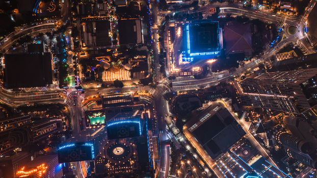 Aerial view of the illuminated city skyline at night featuring glowing skyscrapers busy road networks with light trails and dense urban infrastructure in Jakarta Indonesia.