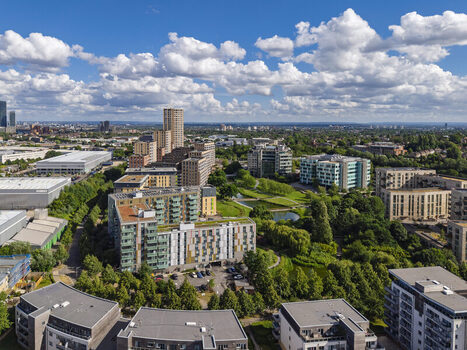 Aerial view of Lakeside Drive featuring modern residential apartment blocks green parkland a small pond and urban infrastructure under a blue sky in London England United Kingdom. Aerial view of Lakeside Drive featuring modern residential apartment blocks green parkland a small pond and urban infrastructure under a blue sky in London England United Kingdom.