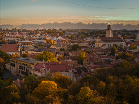 Aerial view of the golden hues of autumn paint the skyline contrasting with the stoic architecture of Vilnius Cathedral and the Old Town s terracotta roofs Vilnius Lithuania. Aerial view of the golden hues of autumn paint the skyline contrasting with the stoic architecture of Vilnius Cathedral and the Old Town s terracotta roofs Vilnius Lithuania.