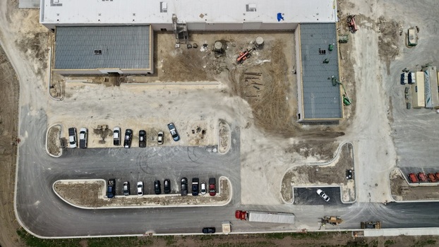 Aerial view of Foundry Lane construction site featuring a large industrial building parked vehicles and heavy machinery on a dirt lot World Golf Village Florida United States.