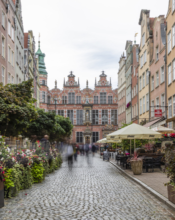 Gdansk Poland 05 September 2026 View of the Great Armoury with its ornate facade cobblestone street outdoor cafe seating and blurred pedestrians in the historic city center. Gdansk Poland 05 September 2026 View of the Great Armoury with its ornate facade cobblestone street outdoor cafe seating and blurred pedestrians in the historic city center.