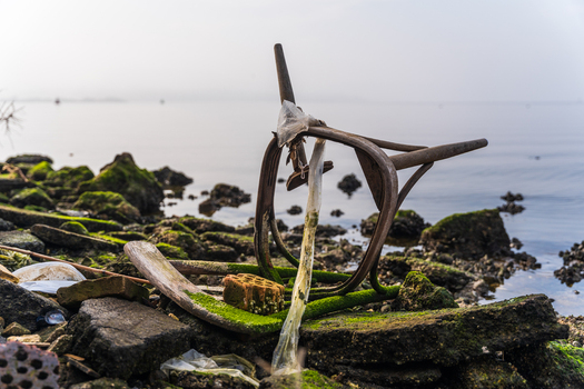 View of an old weathered wooden chair frame resting on the mossy rocky shoreline of Lake Varna Varna Bulgaria. View of an old weathered wooden chair frame resting on the mossy rocky shoreline of Lake Varna Varna Bulgaria.