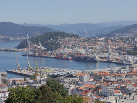 View of the busy Port of Vigo with industrial cranes cargo ships and the city skyline stretching along the coast in Vigo Pontevedra Spain.