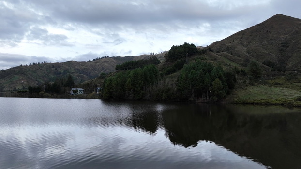 Aerial view of Corani Lake surrounded by lush green hills dense pine forests and a cloudy sky in Chapare Cochabamba Department Bolivia. Aerial view of Corani Lake surrounded by lush green hills dense pine forests and a cloudy sky in Chapare Cochabamba Department Bolivia.