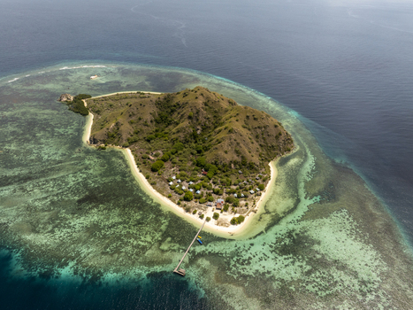 Aerial view of Kanawa Island with lush green hills white sandy beaches and a wooden pier extending into turquoise coral reef waters in Kecamatan Komodo Nusa Tenggara Timur Indonesia. Aerial view of Kanawa Island with lush green hills white sandy beaches and a wooden pier extending into turquoise coral reef waters in Kecamatan Komodo Nusa Tenggara Timur Indonesia.