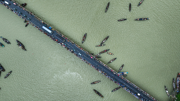 Baghabari Bangladesh 20 August 2022 Aerial view of the Baghabari bridge over the river crowded with people and vehicles surrounded by numerous small wooden boats navigating the water.