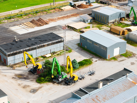 Aerial view of industrial machinery stacks of logs and storage warehouses at a timber supply chain and sustainable forestry facility in Latvia. Aerial view of industrial machinery stacks of logs and storage warehouses at a timber supply chain and sustainable forestry facility in Latvia.
