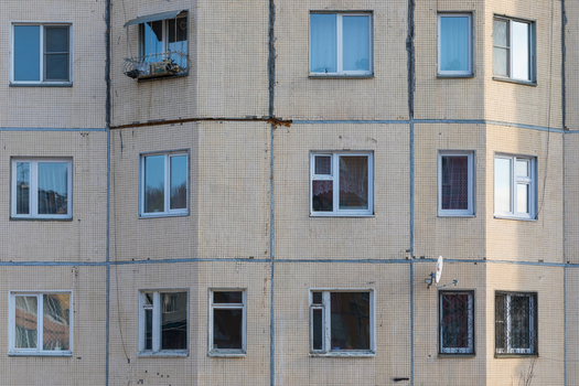 View of the tiled facade of a residential apartment building with multiple windows and a satellite dish in Severobaykalsk Buryatia Russia.