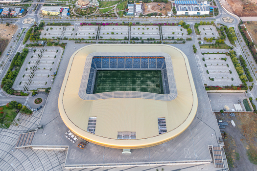Aerial view of Sammy Ofer Stadium with its distinctive golden roof and green pitch surrounded by paved plazas and parking areas in Haifa Haifa District Israel. Aerial view of Sammy Ofer Stadium with its distinctive golden roof and green pitch surrounded by paved plazas and parking areas in Haifa Haifa District Israel.