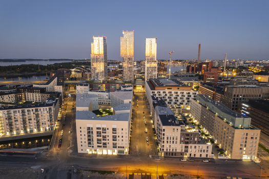 Aerial view of modern high rise towers in the Kalasatama district at twilight with contemporary residential architecture city lights and harbor views in Helsinki Uusimaa Finland.