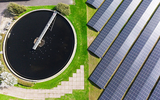 Aerial view of a circular water treatment tank and adjacent solar panel array in Schagerbrug Noord Holland Netherlands. Aerial view of a circular water treatment tank and adjacent solar panel array in Schagerbrug Noord Holland Netherlands.