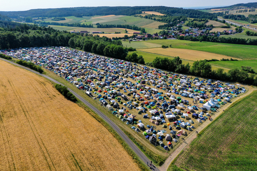 Geiselwind Germany 21 June 2025 Aerial view of Eventzentrum Strohofer Geiselwind musichall campsite with hundreds of colorful tents spread across a field near a forest. Geiselwind Germany 21 June 2025 Aerial view of Eventzentrum Strohofer Geiselwind musichall campsite with hundreds of colorful tents spread across a field near a forest.