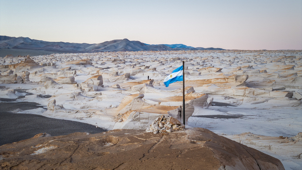 Aerial view of the vast white pumice stone formations with an Argentine flag waving in the foreground in El Penon Catamarca Province Argentina. Aerial view of the vast white pumice stone formations with an Argentine flag waving in the foreground in El Penon Catamarca Province Argentina.