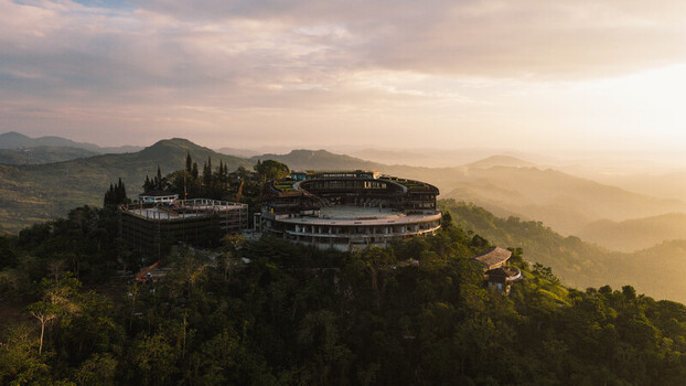 Cebu City Philippines 20 May 2026 Aerial view of the circular building in Busay surrounded by lush tropical forests and rolling hills during a golden sunset.