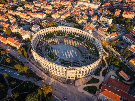 Aerial view of the ancient Roman amphitheater a majestic oval structure standing in stark contrast against the warm terracotta rooftops and lush greenery Pula Istria County Croatia.