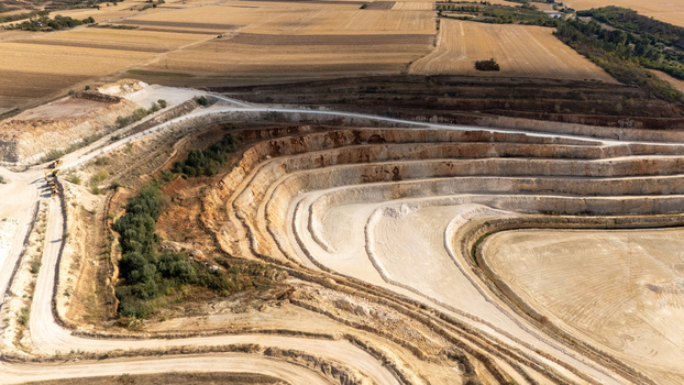 Aerial view of the open pit limestone quarry showing terraced excavation levels exposed white rock and surrounding agricultural fields in Besenovo Vojvodina Serbia. Aerial view of the open pit limestone quarry showing terraced excavation levels exposed white rock and surrounding agricultural fields in Besenovo Vojvodina Serbia.