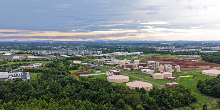 Aerial view of a water treatment facility with large circular storage tanks and industrial buildings surrounded by lush green forests and suburban development in Ashburn Virginia United States.
