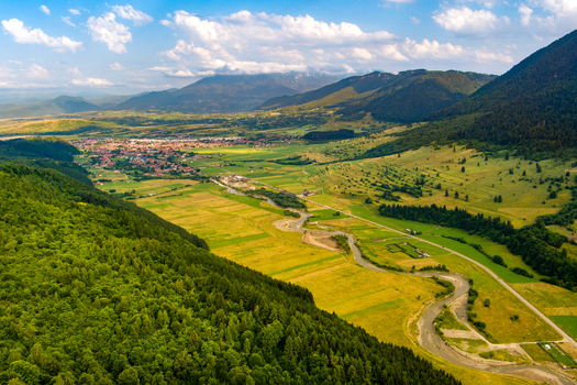 Brasov Romania 21 September 2026 Aerial view of the valley landscape surrounding Brasov featuring a winding river lush forests agricultural fields and distant mountains under a blue sky. Brasov Romania 21 September 2026 Aerial view of the valley landscape surrounding Brasov featuring a winding river lush forests agricultural fields and distant mountains under a blue sky.