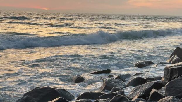View of ocean waves crashing on rocks at sunset United States. View of ocean waves crashing on rocks at sunset United States.